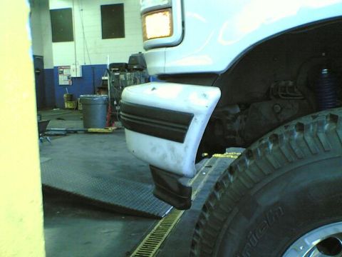 1996 Ford Bronco - Close-up view of the front fender and tire of a white 1996 Ford Bronco in a garage setting.