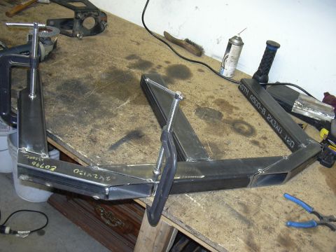 1991 Ford Bronco - Metal parts being welded together on a workbench with various tools present.