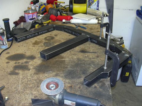 1991 Ford Bronco - Metal parts are clamped together on a workbench, ready for welding, with an angle grinder nearby.