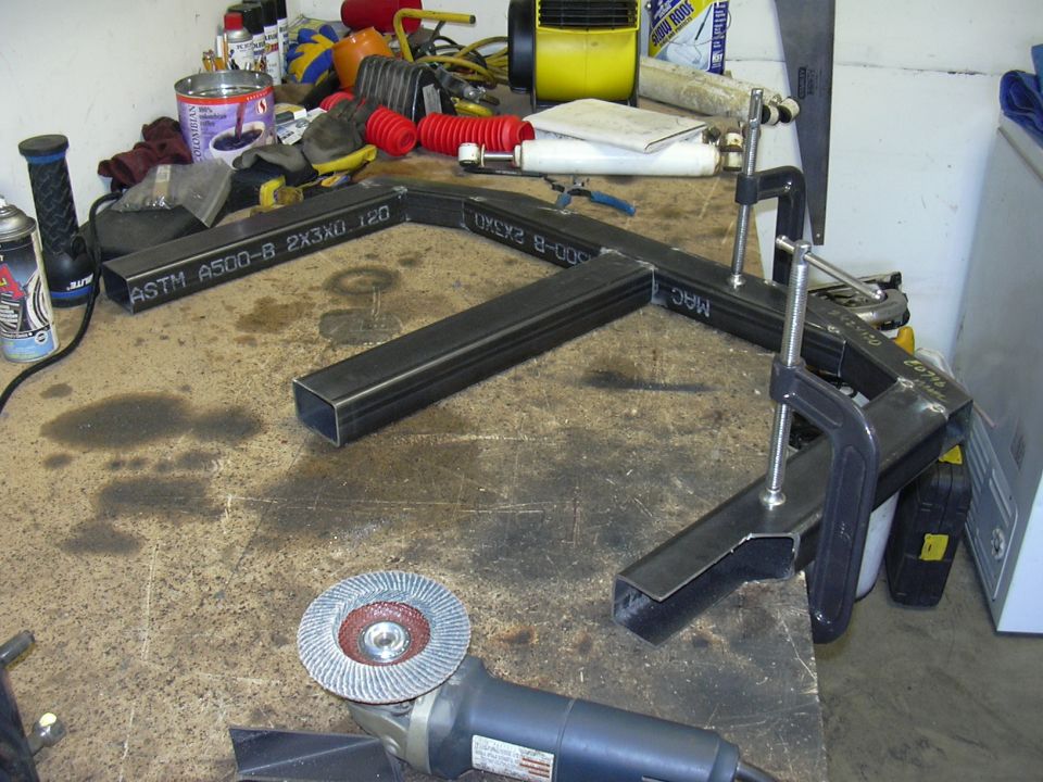 Metal tubing, clamps, and angle grinder on a workbench