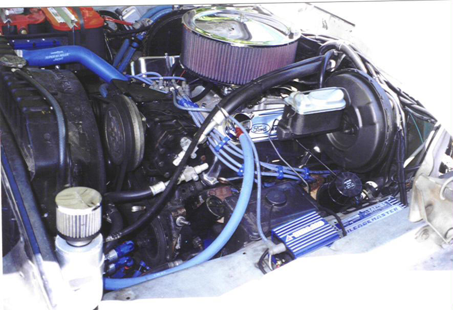 Engine bay of a 1979 Ford Bronco with a Ford-branded engine, chrome air cleaner, and blue hoses