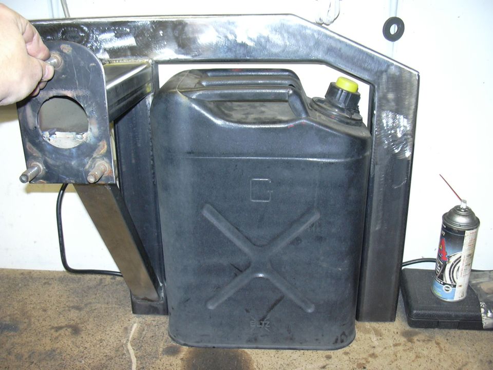 Bare steel fabricated jerry can and spare tire swing-out carrier holding a black fuel can