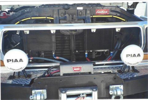 1979 Ford Bronco - Close-up of a vehicle's front end, auxiliary lights, a winch, and engine components.