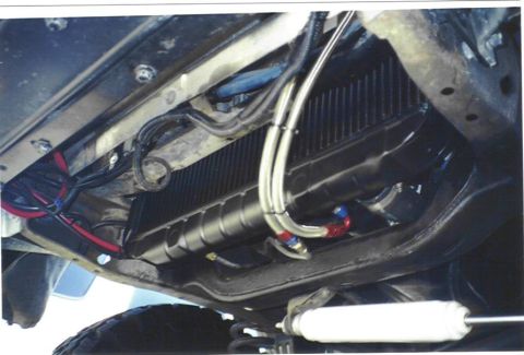 1979 Ford Bronco - Vehicle's undercarriage with transmission cooler and associated plumbing visible.