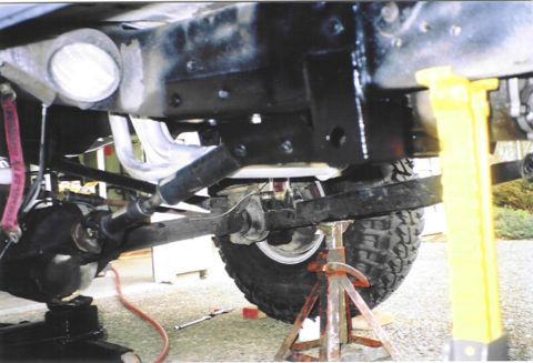1979 Ford Bronco - The vehicle's undercarriage is visible, supported by jack stands and a yellow support.