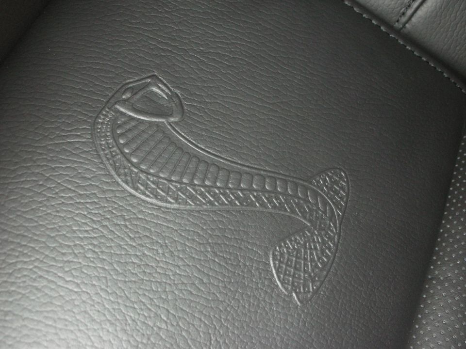 Embossed Shelby Cobra snake logo on black leather upholstery