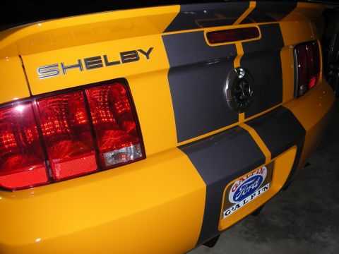 1998 Ford Crown Victoria - Rear quarter of a yellow car with a black racing stripe, chrome SHELBY badge, round taillights, and a Galpin Ford dealer plate.