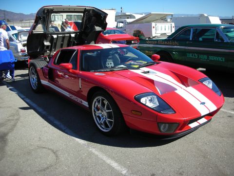 1998 Ford Crown Victoria - Red Ford GT supercar with white center stripes and its rear clamshell raised, parked at an outdoor automotive show.