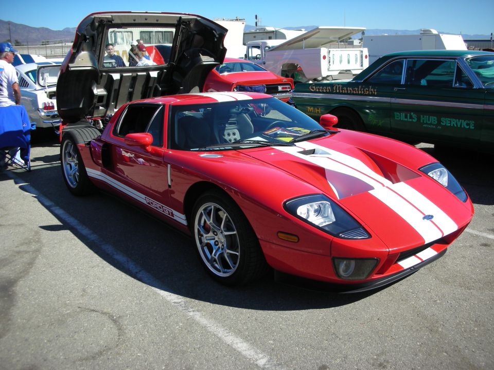 Red Ford GT with white stripes and open clamshell rear at an outdoor show