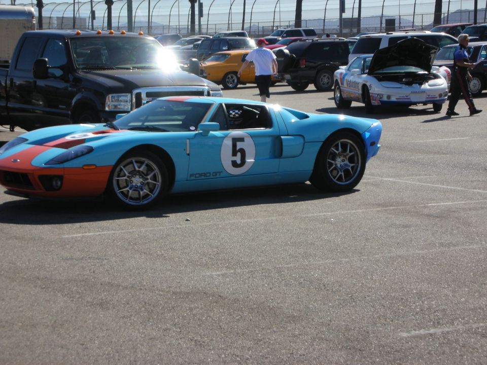 Light blue Ford GT with orange stripes and number 5 in a track parking lot