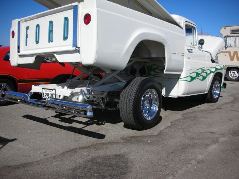 1998 Ford Crown Victoria - Rear of a customized white Ford pickup truck with FORD tailgate lettering, green flame graphics, chrome wheels, and a tube bumper.