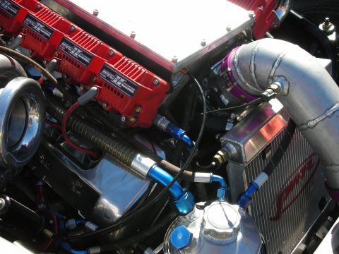 1998 Ford Crown Victoria - Detailed view of a polished turbocharged engine with red valve covers, braided lines, and blue anodized AN fittings.