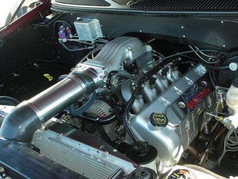 1998 Ford Crown Victoria - engine bay showing a centrifugal-supercharged motor with a large polished intake tube and a black Ford Racing valve cover.