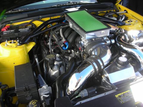 1998 Ford Crown Victoria - yellow car's engine bay with a green panel air filter, chrome charge piping and a yellow coolant reservoir.