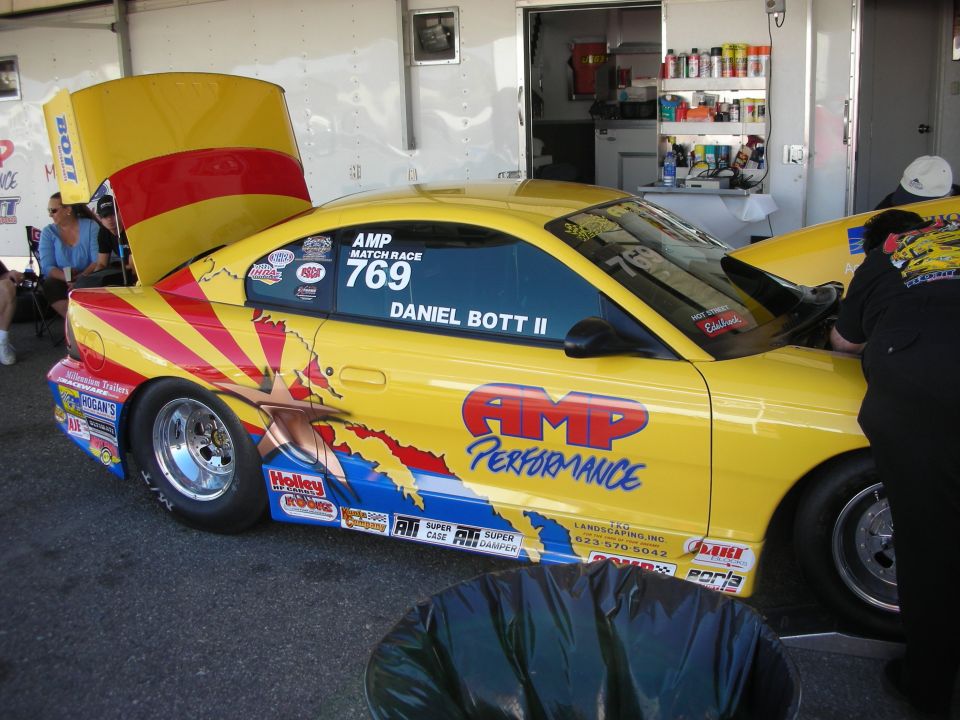 Yellow drag Mustang with AMP Performance graphics and raised hood in pit