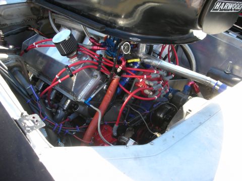 1998 Ford Crown Victoria - race engine bay with extensive red and blue braided fuel lines and a Harwood-branded firewall panel.