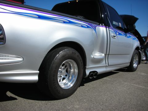 1998 Ford Crown Victoria - silver Ford pickup with purple flame graphics, lowered stance and a polished wheel on a rear drag slick.