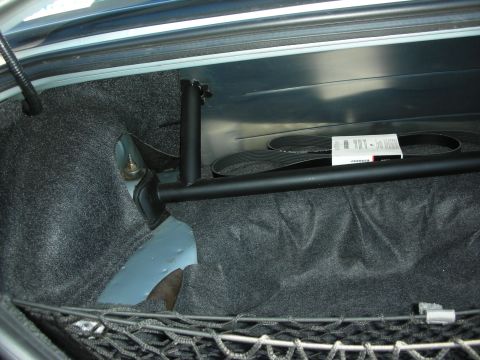 1998 Ford Crown Victoria - Carpeted vehicle trunk fitted with a black strut tower brace and a cargo net along the rear edge.