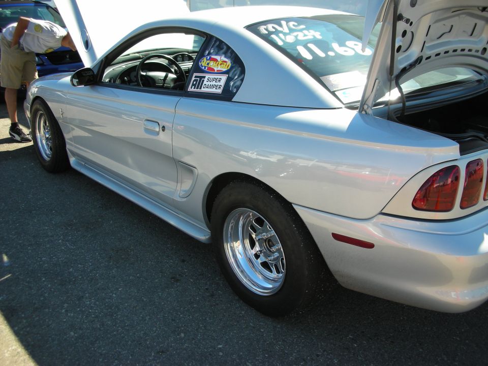 Silver Ford Mustang coupe in profile with polished drag wheels at a show