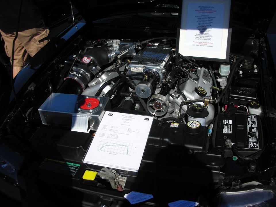 Engine bay with supercharger and a clipboard dyno sheet on display