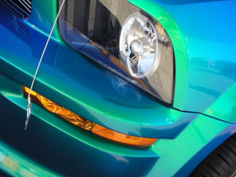 1998 Ford Crown Victoria - Detail of the headlight and amber front turn signal on a color-shifting blue-green custom Mustang.