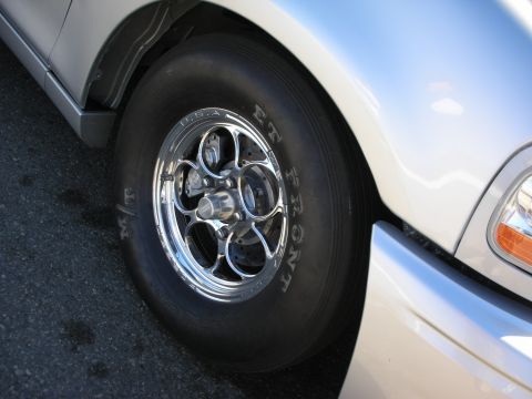 1998 Ford Crown Victoria - close-up of a polished five-spoke front drag wheel wrapped in a skinny slick tire stamped RT FRONT on a silver vehicle.