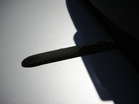 1998 Ford Crown Victoria - single black windshield wiper arm rests against the base of a silver-painted hood under harsh sunlight.
