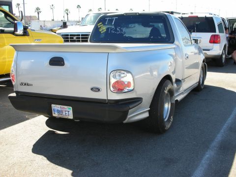 1998 Ford Crown Victoria - Rear three-quarter view of a silver Ford SVT regular-cab pickup with a bed cover and a California plate reading 1 BULET.