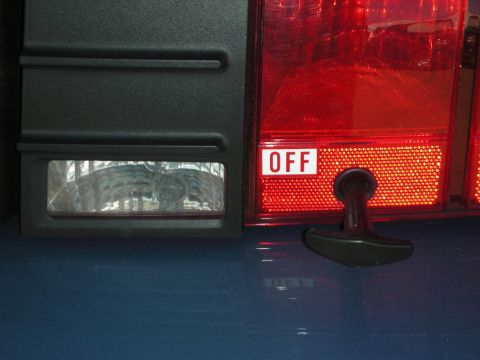 1998 Ford Crown Victoria - trunk panel detail showing a black pull-style battery cutoff switch labeled OFF next to a red tail light lens.
