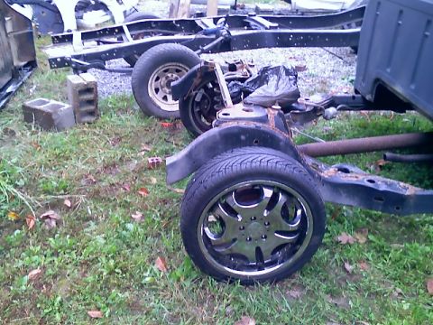 2002 Ford Crown Victoria - The chassis and frame of a vehicle are visible, with chrome wheels on the ground.