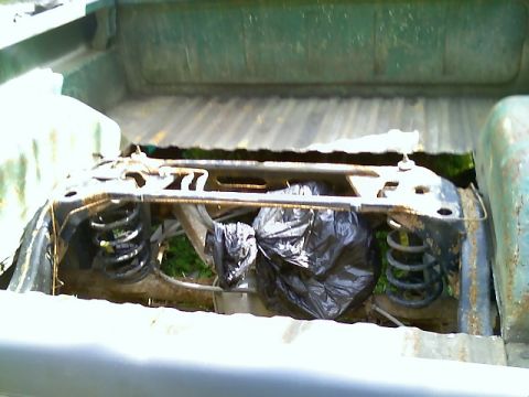 2002 Ford Crown Victoria - The rear suspension system of a pickup truck is visible, with trash bags obscuring some of the components.