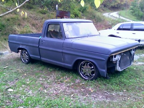 2002 Ford Crown Victoria - A gray Ford pickup truck sits on grass, missing its grille and sporting custom wheels.