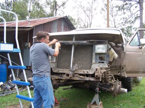 1981 Ford Bronco - A man works on the front end of a disassembled brown Ford truck, which appears to be from the early 1980s.
