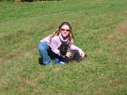 1985 Ford LTD Crown Victoria - A woman kneels in the grass, petting her black dog on a sunny day.