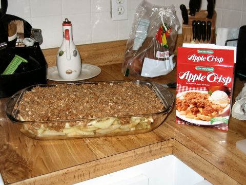 1985 Ford LTD Crown Victoria - Ingredients for apple crisp are laid out on a kitchen counter, including a prepared dessert and a box of mix.