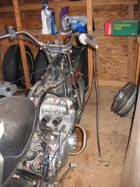 1985 Ford LTD Crown Victoria - Disassembled motorcycle engine and frame in a workshop setting, surrounded by spare parts.