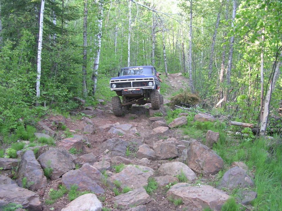 Blue 1977 Ford F-150 navigating a rocky off-road trail