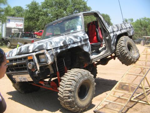 1979 Ford Bronco - This heavily modified truck is attempting to climb a metal ramp, its off-road capabilities.