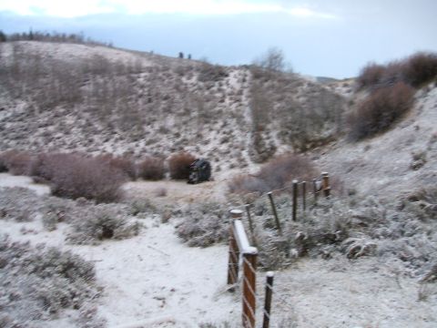 1992 Ford Ranger - A vehicle lies on its side in a snow-covered rural area, partially obscured by bushes.