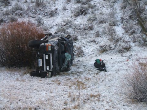 1992 Ford Ranger - A black 1992 Ford Ranger lies overturned on its side in a snowy, brush-covered area.