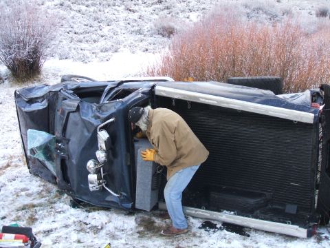 1992 Ford Ranger - A person inspects an overturned pickup truck in a snowy, rural landscape.