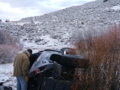 1992 Ford Ranger - A pickup truck has overturned in a snowy, brushy area with a person inspecting the damage.