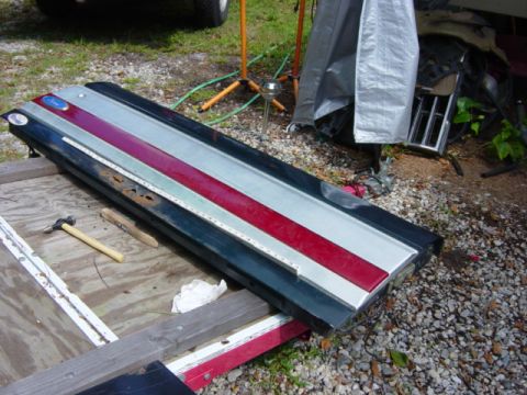 1991 Ford Bronco - A disassembled tailgate with red and silver stripes lies on a trailer, showing signs of rust and wear.