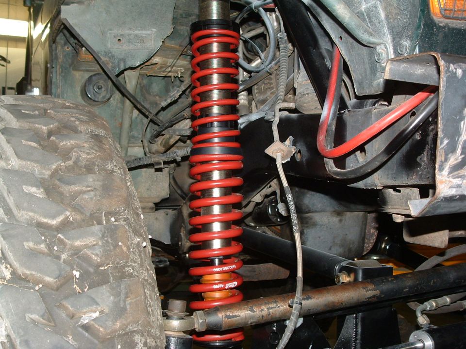 Close-up of a red coilover shock absorber and large tire on a vehicle