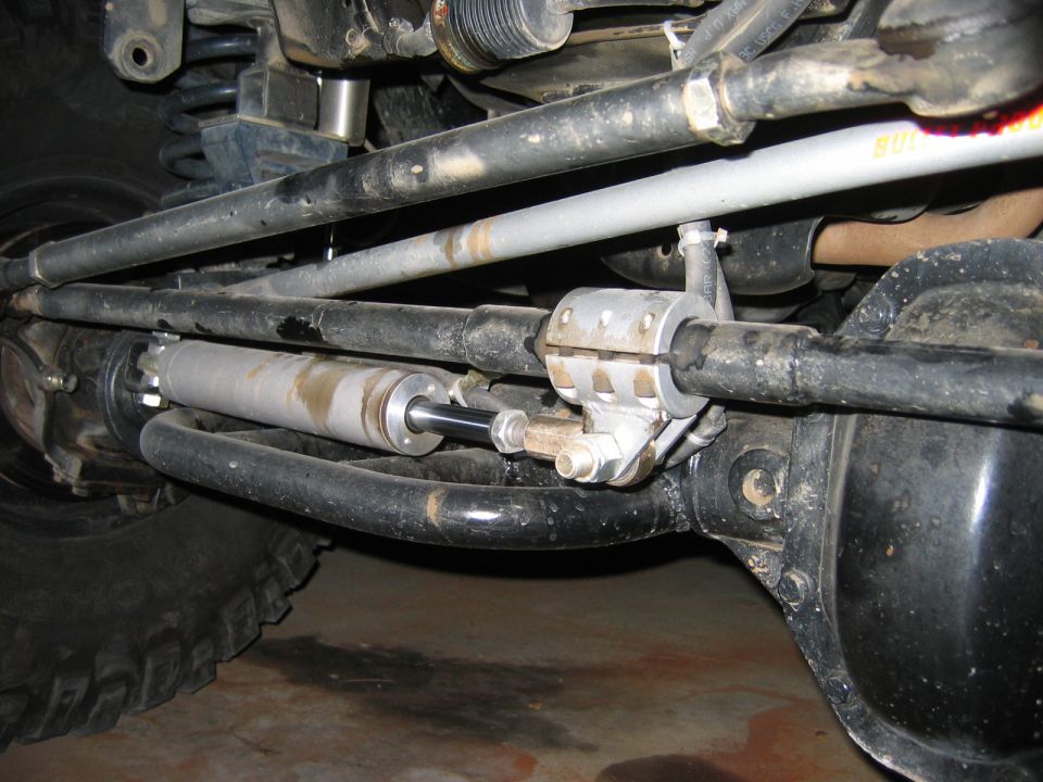 Front axle underside with silver dual steering stabilizer mounted to tie rod