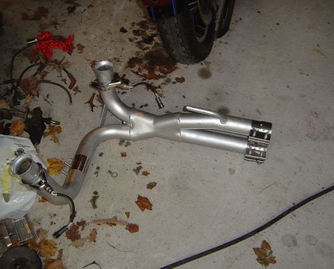 1986 Ford Bronco - An exhaust system with dual tips and attached sensor wires lies on a concrete floor.