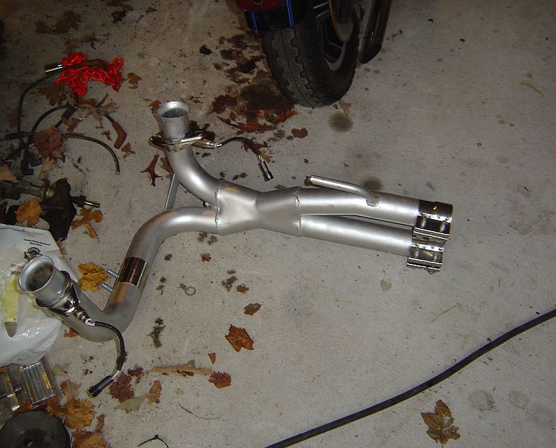Motorcycle two-into-two exhaust system with chrome tips laid on a garage floor