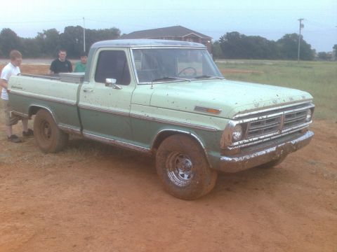 1991 Ford Bronco - A vintage Ford pickup truck, possibly from the early 1970s, sits on a muddy, unpaved surface.