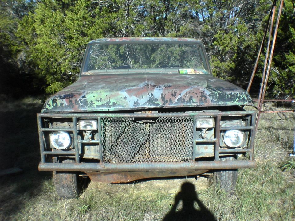 Rusty truck front with custom grille guard and camouflage paint remnants