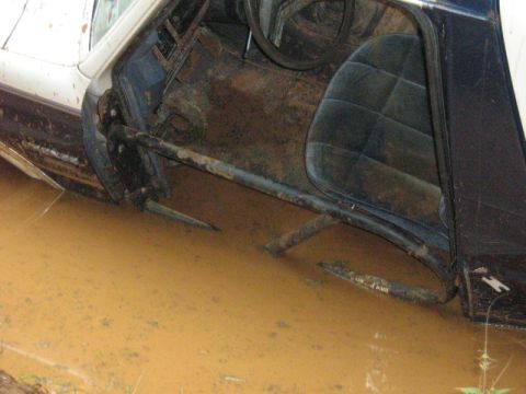 1986 Ford Bronco - Vehicle interior and side are submerged in muddy water, indicating it is stuck off-road.